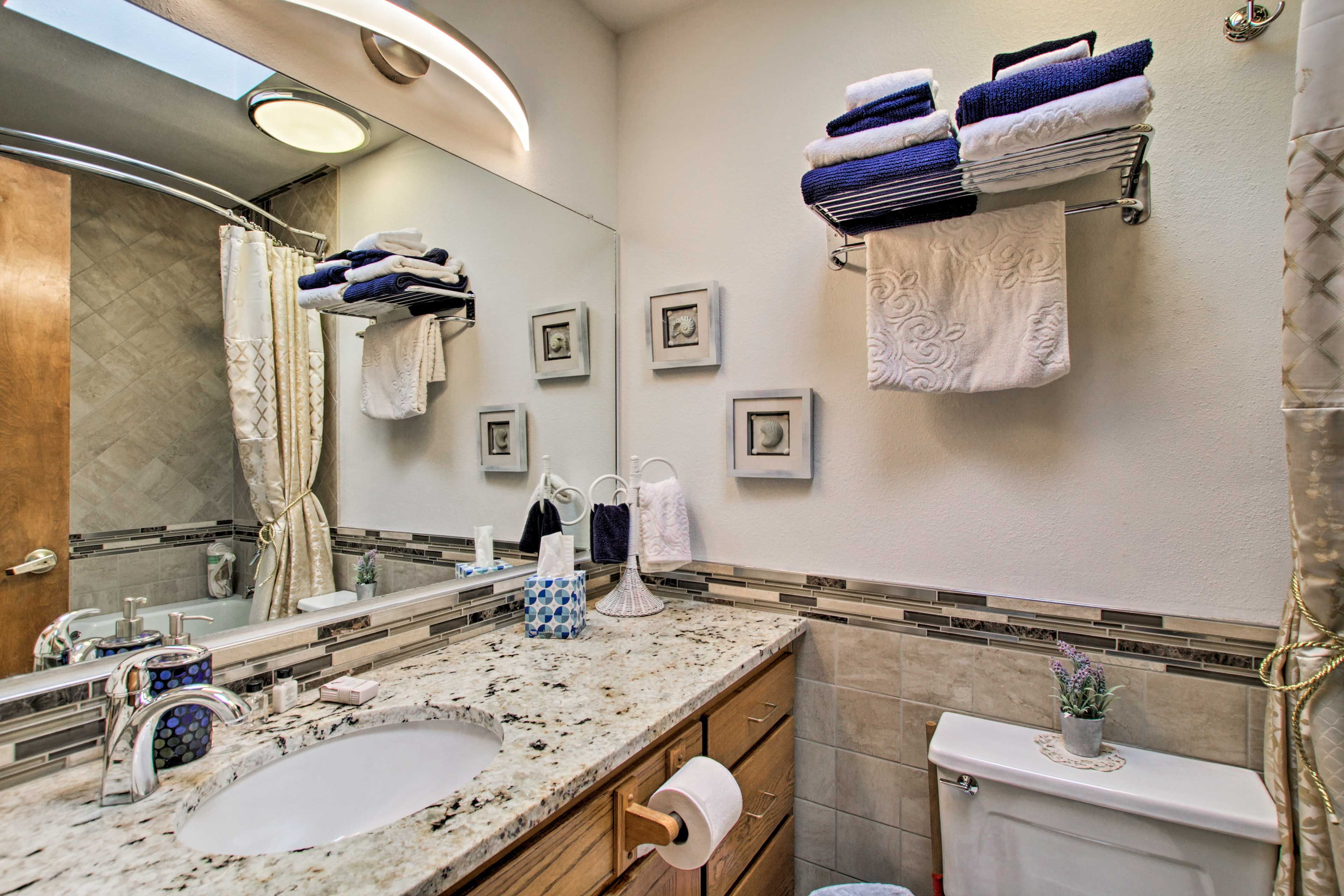 A bathroom with a marble sink, a toilet, and a shower area. There are towels and toiletries visible.