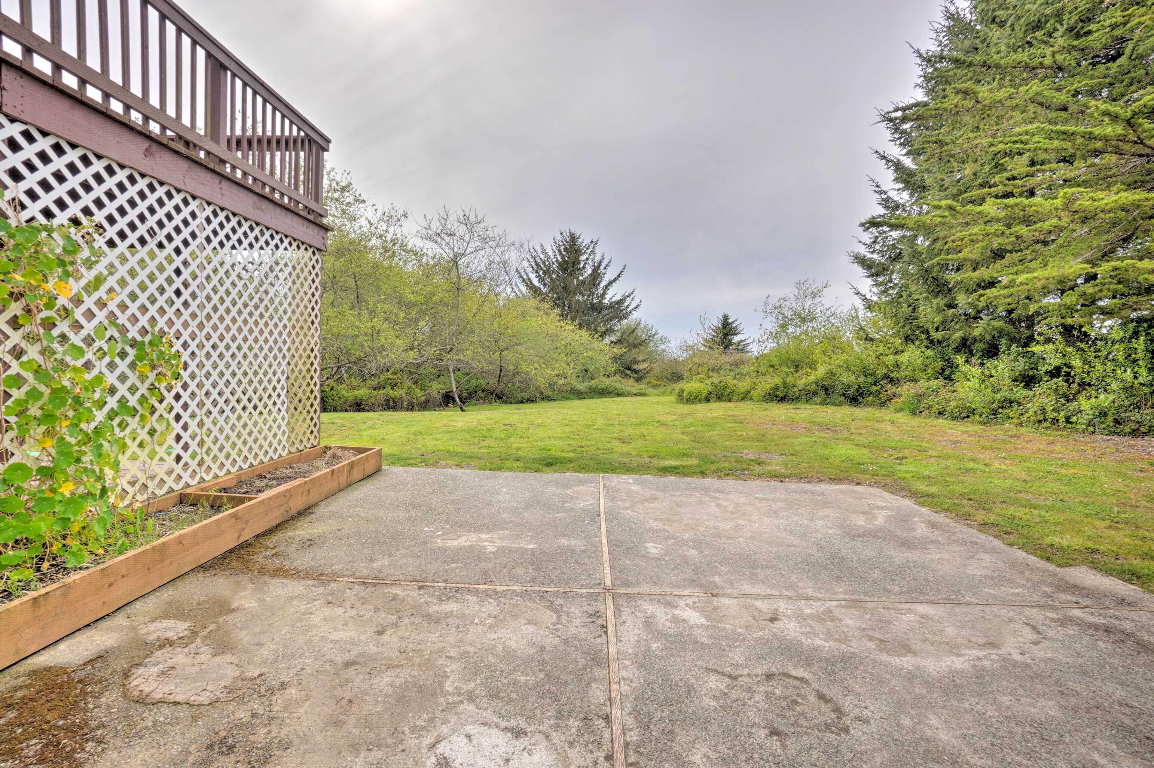 A concrete patio with a wooden planter box and a white lattice fence.