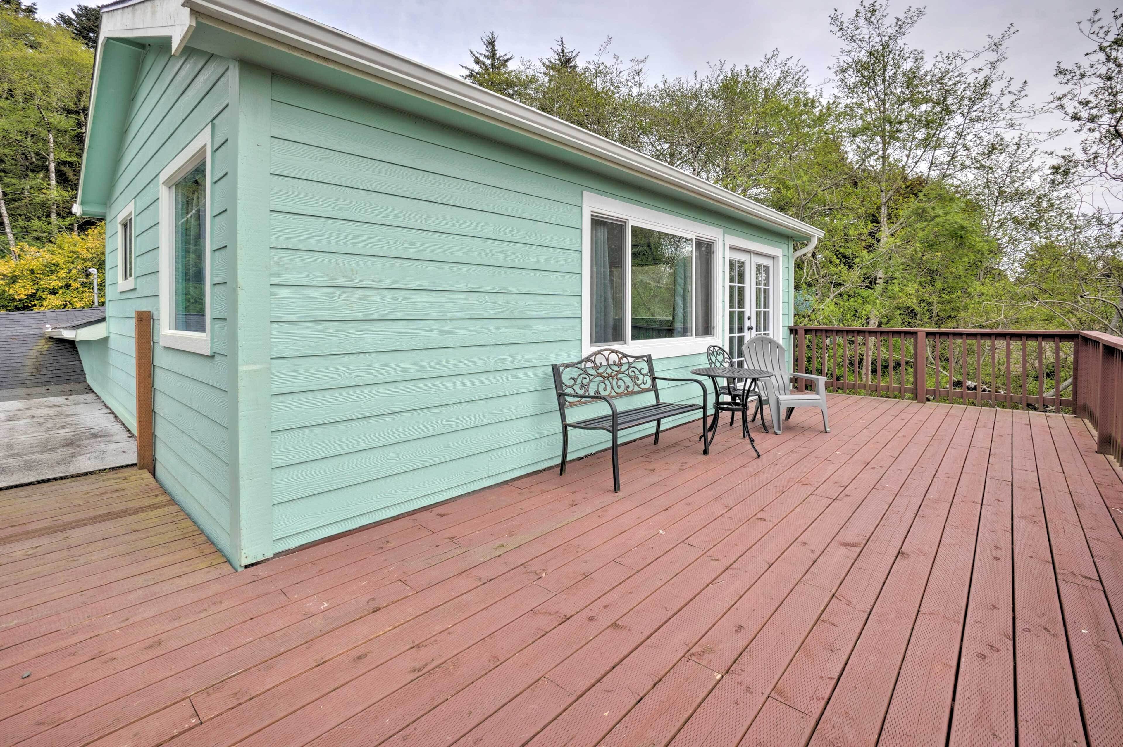 A light green building with a deck and two chairs.