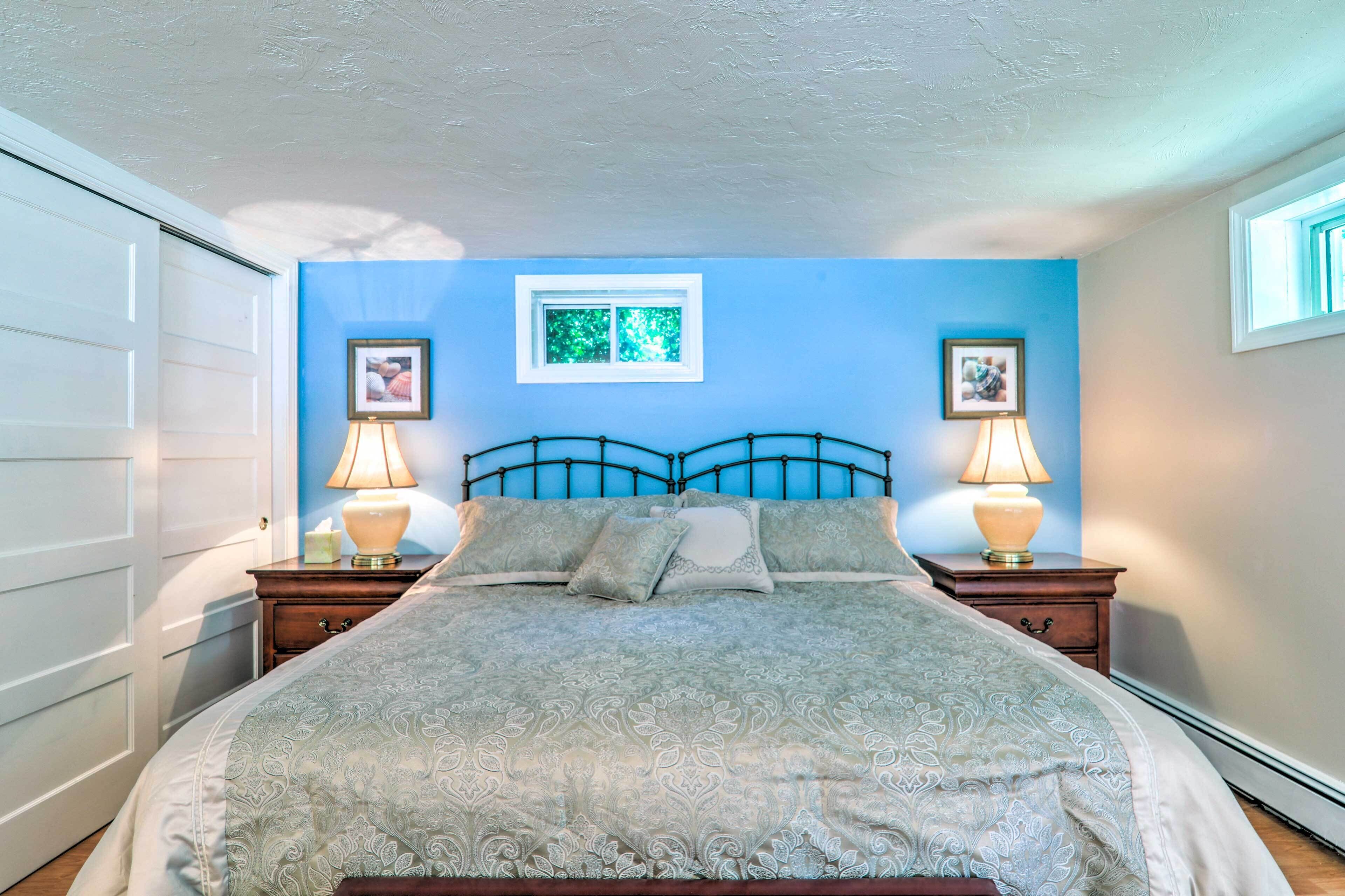 A bedroom with a bed, two bedside tables with lamps, a window, and a door.
