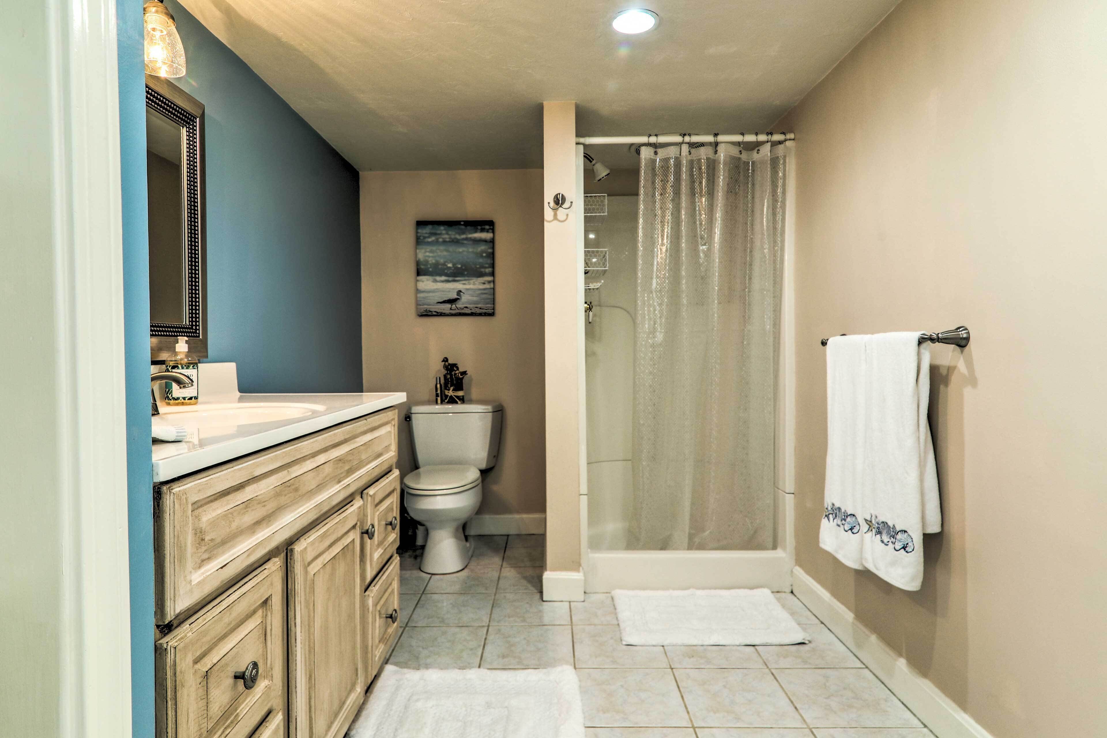 A bathroom with a white sink, beige vanity, a toilet, a shower with a glass door, and a towel hanging on the wall.