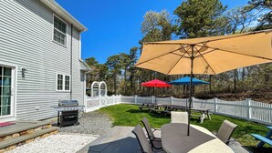A patio with a table and chairs, a barbecue grill, and picnic tables.