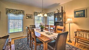 A dining room with a wooden table, chairs, a chandelier, and a fireplace.