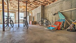 A spacious indoor area with a concrete floor, wooden ceiling beams, and bicycles parked against the walls.