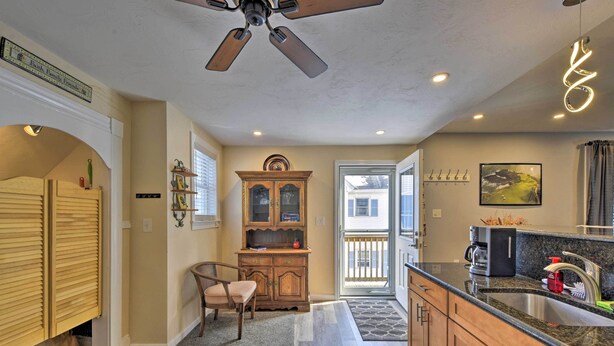A kitchen with wooden cabinets, a built-in oven, a ceiling fan, and a window with a view of a house.