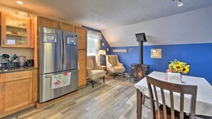 A kitchen with wooden cabinets, a stainless steel refrigerator, and a dining area with a table and chairs.