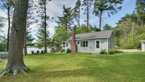 A house with a chimney, surrounded by a grassy yard and tall trees. - Peaceful Long Pond Cottage w/ Dock & Views (Freetown)