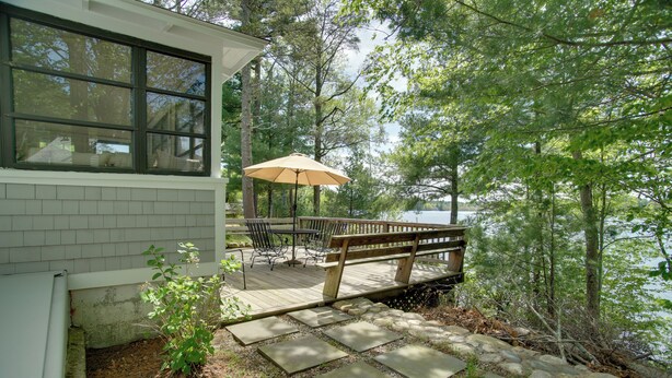 A wooden deck with a table and chairs, overlooking a lake. - Peaceful Long Pond Cottage w/ Dock & Views (Freetown)