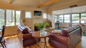 A spacious living room with leather sofas, a wooden coffee table, and a TV mounted on the wall. - Peaceful Long Pond Cottage w/ Dock & Views (Freetown)