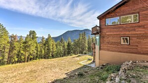 A wooden cabin with a view of a forest and mountains.