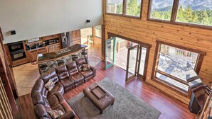 A spacious living area with a leather sofa, a coffee table, and a kitchen area with wooden cabinets and a large window offering a mountain view.