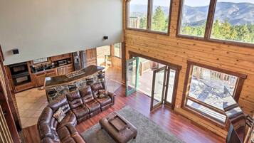 A spacious living area with a leather sofa, a coffee table, and a kitchen area with wooden cabinets and a large window offering a mountain view.