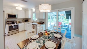 A modern kitchen with white cabinetry, stainless steel appliances, and a dining area with a table set for four. - Lush Punta Gorda Escape: Private Pool + Lanai (Punta Gorda)