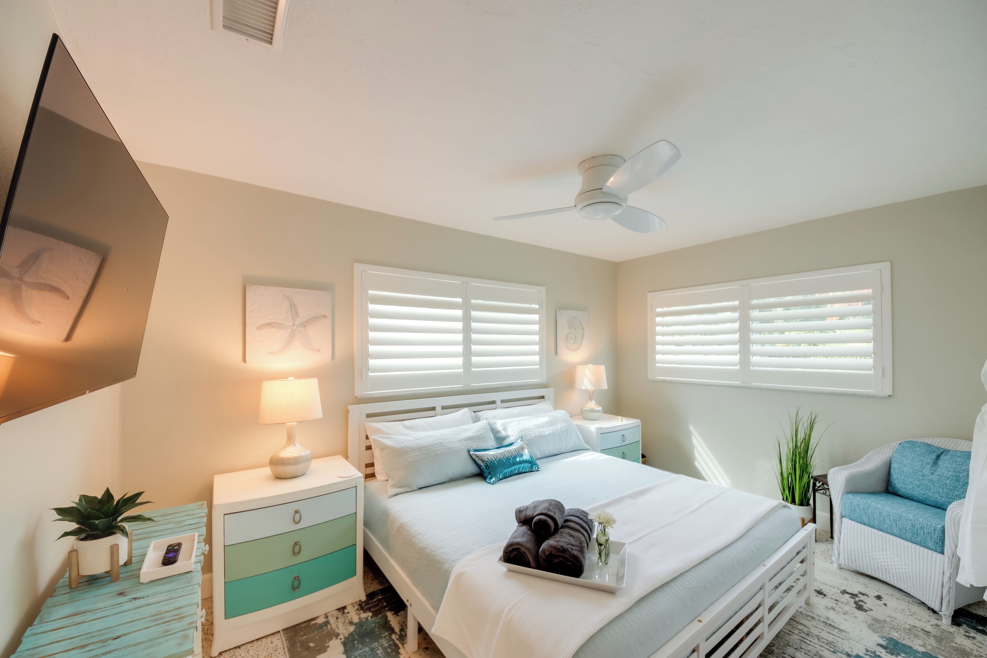 A bedroom with a bed, nightstands, a ceiling fan, and a chair.