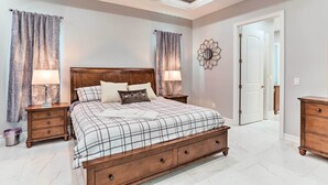 Un dormitorio con una cama grande, dos mesitas de noche, un cabecero de madera y una puerta.