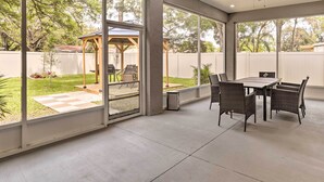 Un patio techado con una mesa y sillas, ventanas amplias y un ventilador de techo.