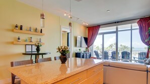 Cozinha moderna com bancada de granito, armários de madeira e área de refeições com cadeiras.