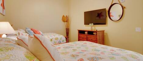 A bedroom with two beds, a dresser, a mirror, and a ceiling fan.