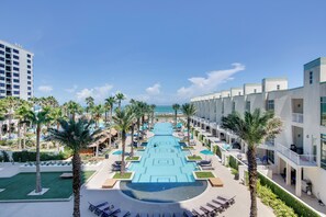 Un complexe hôtelier doté d’une piscine centrale, de palmiers et offrant une vue sur l’océan.