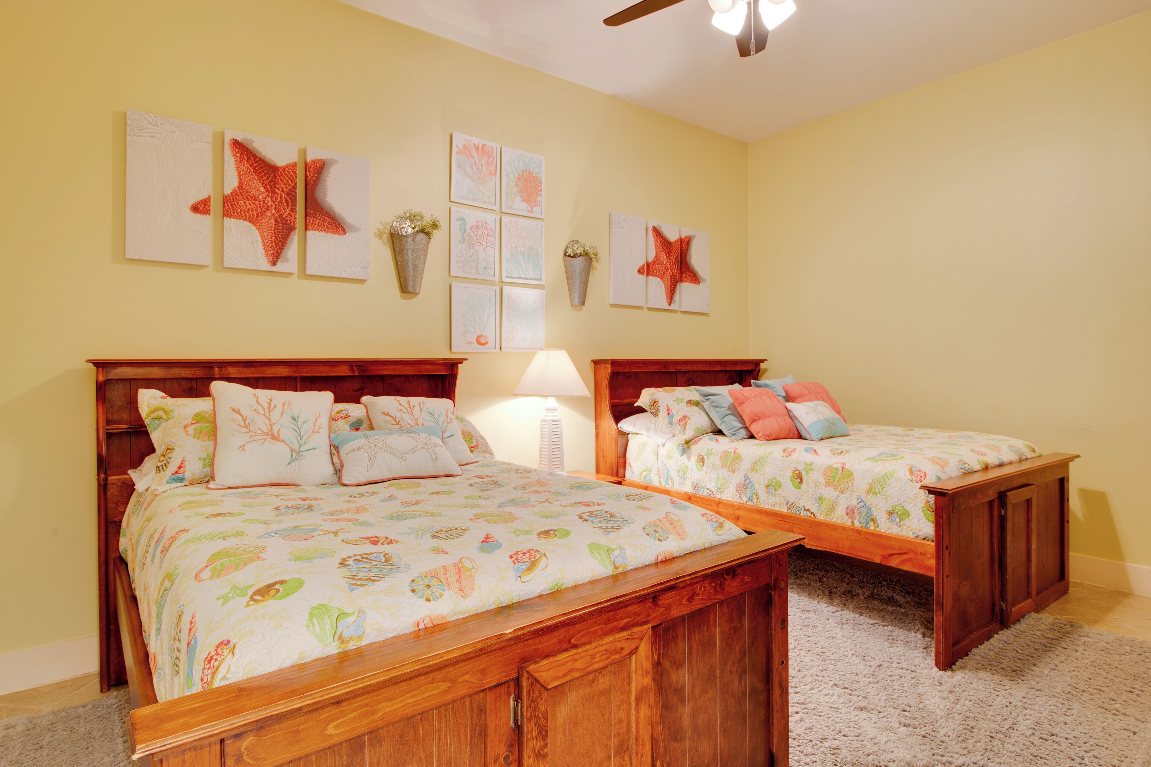 A bedroom with two wooden beds, a ceiling fan, and wall art.