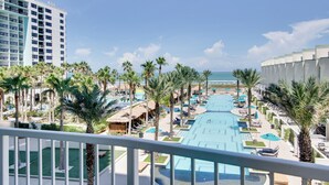 Um resort com uma piscina grande, palmeiras e vista para o oceano.