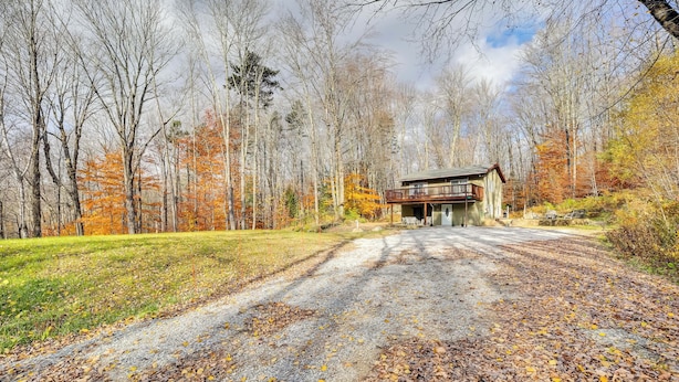 Un chalet rustique doté d’un porche, entouré d’un feuillage automnal et bordé d’une allée en gravier.