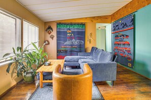 A living room with a sofa, a coffee table, a potted plant, and a wall with indigenous art. - Secluded Port Townsend Retreat: Pets Welcome! (Port Townsend)