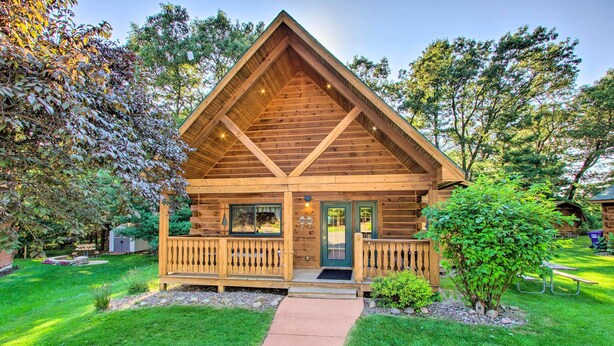 A log cabin with a wooden porch, a front door, and a small front yard with a pathway leading to the entrance. - Pet-friendly Warrens Cabin w/ Fire Pit! (Warrens)