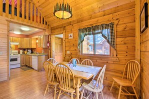 Cozy cabin-style interior with a central dining area, wooden table, and six chairs.
