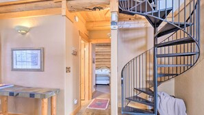 A wooden interior with a spiral staircase, a framed picture on the wall, and a small table. - Mountain Views & Fire Pit: Granby Retreat! (Granby)