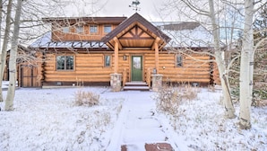 A log cabin with a green door, a chimney, and a snow-covered path leading to the entrance. - Mountain Views & Fire Pit: Granby Retreat! (Granby)