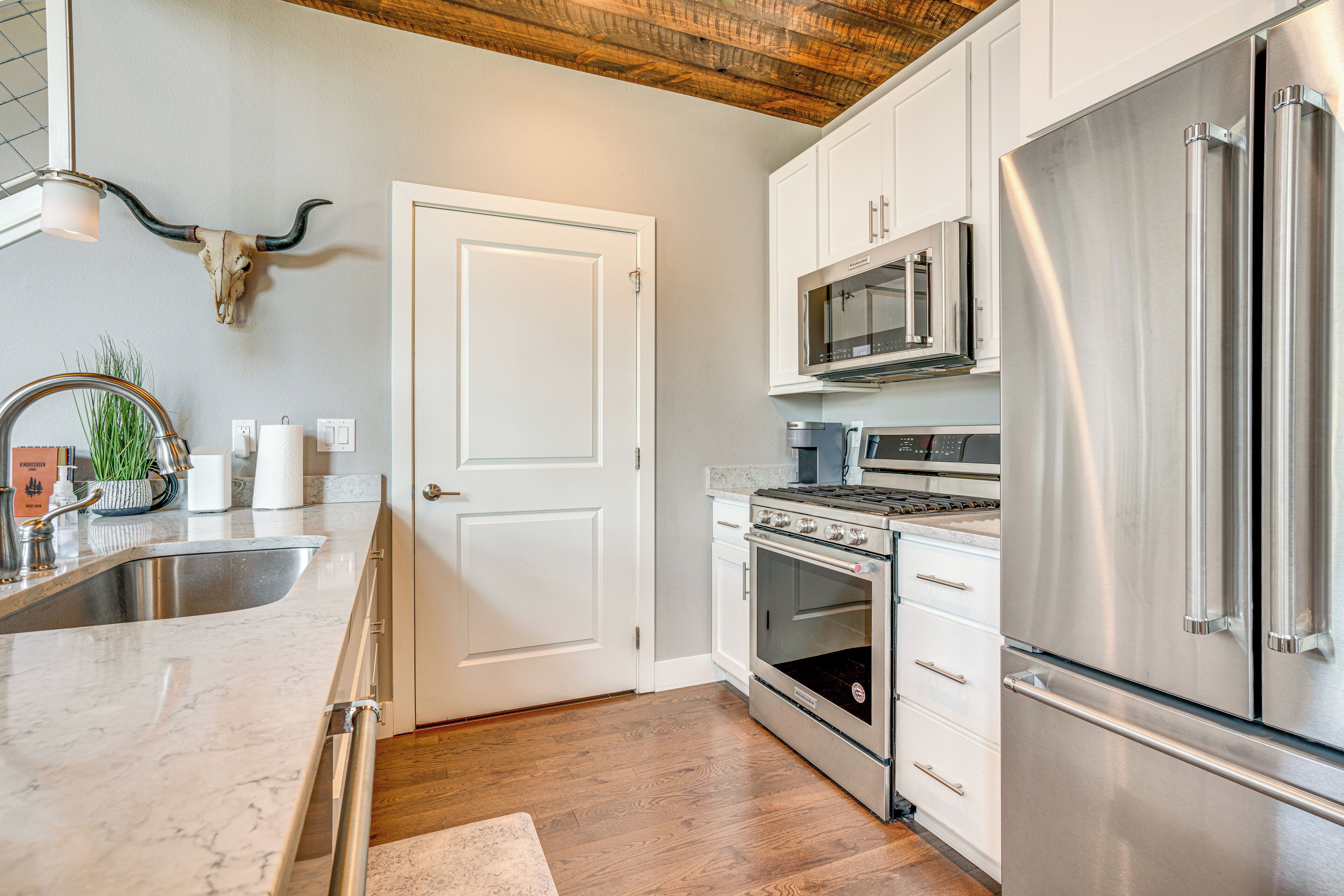A kitchen with white cabinets, stainless steel appliances, a microwave, oven, and a refrigerator.