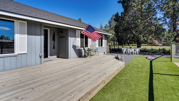 Ein Haus mit einer Holzterrasse, einem Rasen und einer Flagge.