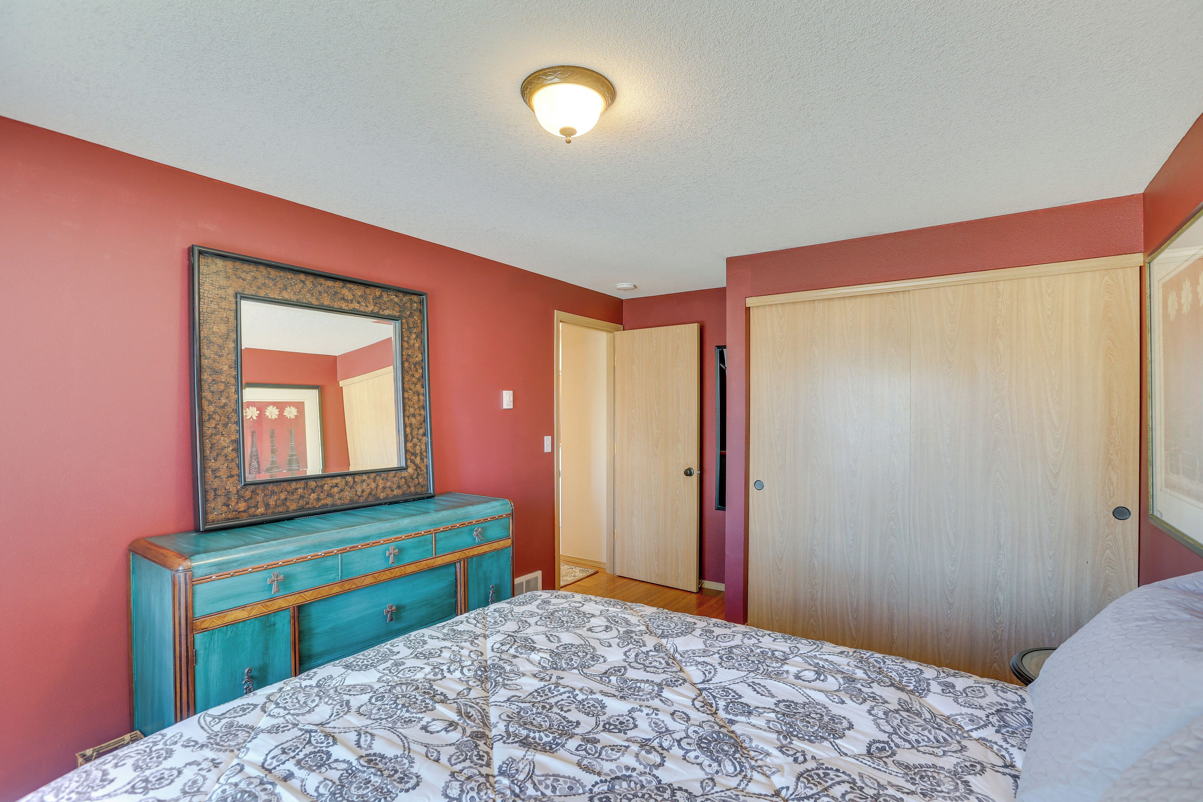 Une chambre à coucher avec un lit, une commode, un miroir et une porte.