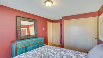 Une chambre à coucher avec un lit, une commode, un miroir et une porte.