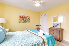 Quarto com cama, cômoda, cadeira e um quadro na parede.