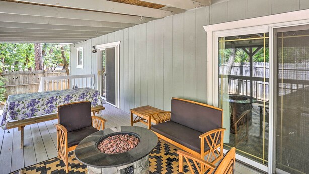 A covered patio with a fire pit, wooden furniture, and a view of the backyard. - Charming Shasta Lake Retreat: Boat, Hike & Fish! (Lakehead)