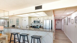 A modern kitchen with a central island, bar stools, stainless steel appliances, and a tiled backsplash. - PCB Vacation Rental w/ Sweeping Ocean Views! (Panama City Beach)