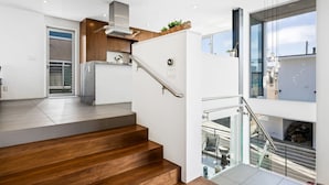 A modern kitchen with a stainless steel range hood, wooden cabinets, and a built-in oven.