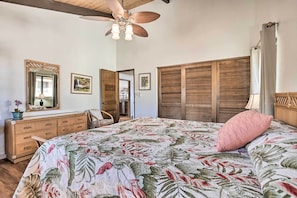 Een slaapkamer met een bed, een dressoir, een spiegel en een plafondventilator.