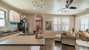 A spacious living area with a large island, a kitchen with white cabinets, and a ceiling fan. - Hawaiian Hideaway w/ Yard < 2 Miles to Hilo Bay! (Hilo)