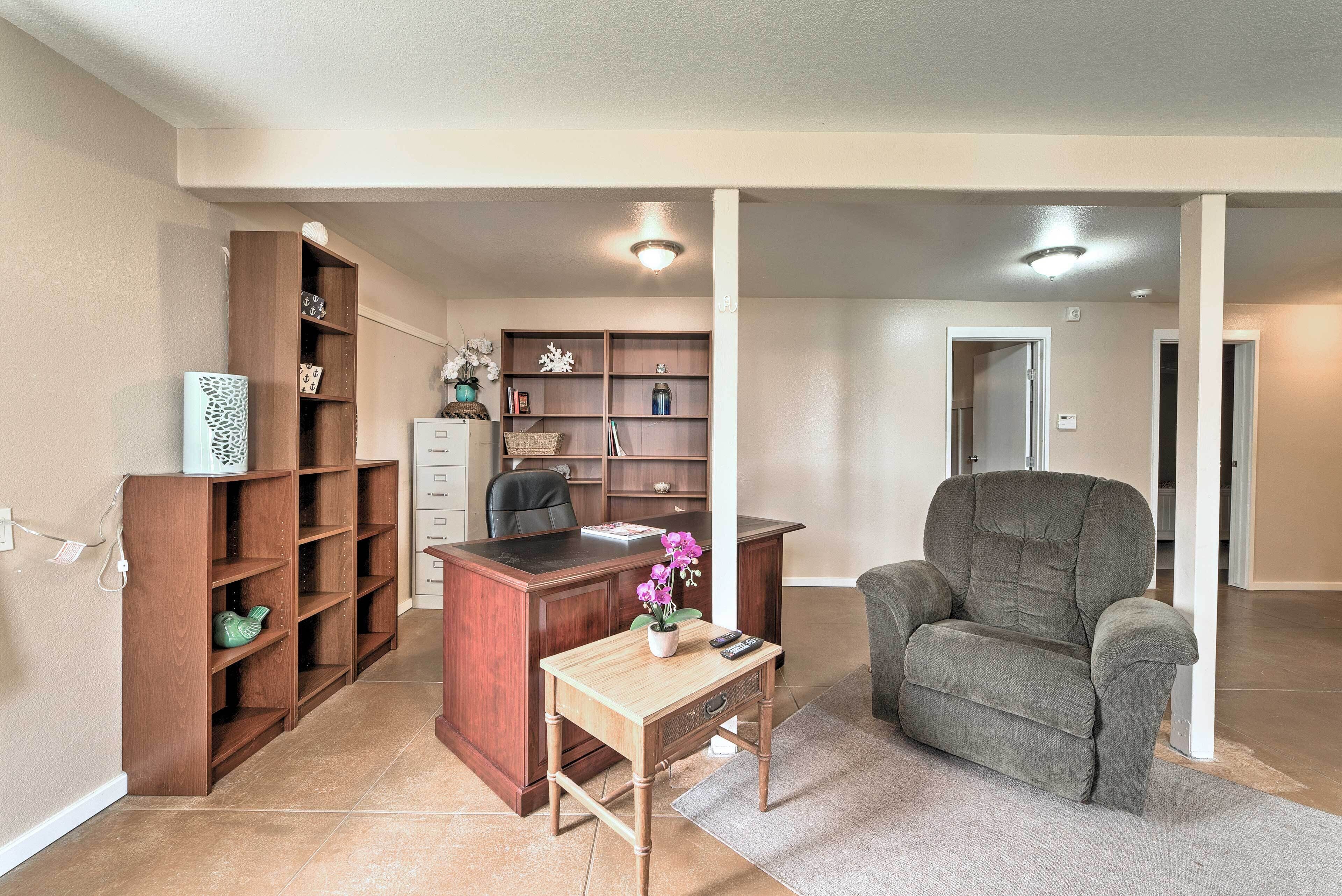 A home office with a desk, chair, and shelving units.