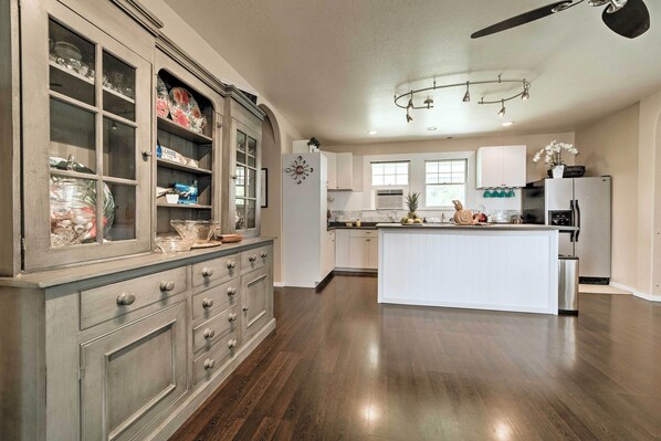 A spacious kitchen with a central island, a built-in cabinet with glass doors, and a ceiling fan. - Hawaiian Hideaway w/ Yard < 2 Miles to Hilo Bay! (Hilo)