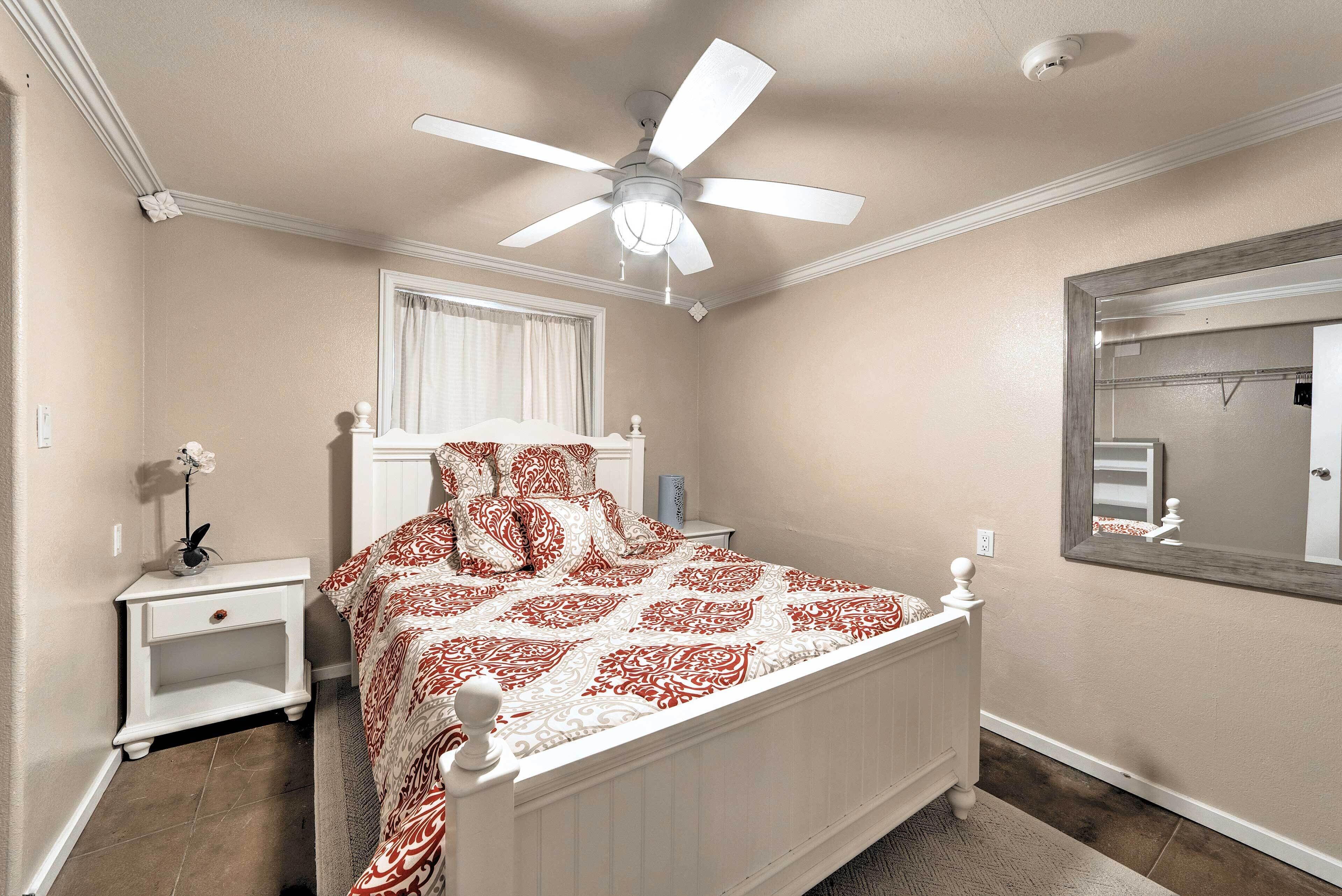 A bedroom with a bed, nightstand, and a ceiling fan.