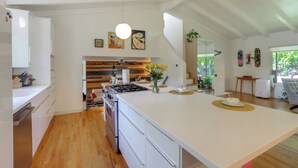 Una cocina moderna con una isla grande, piso de madera, armarios blancos y una isla central con un jarrón de flores.