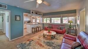 A spacious living room with a red leather couch, a coffee table, and a ceiling fan. - Vintage Las Vegas Oasis < 3 Mi to the Strip! (Las Vegas)