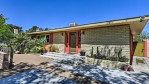 A two-story house with a red door, a brick exterior, and a small front yard with cacti and a potted plant. - Vintage Las Vegas Oasis < 3 Mi to the Strip! (Las Vegas)