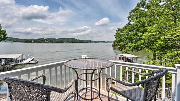 A balcony with wicker furniture overlooking a lake, a dock, and a distant shoreline. - Sunny 'providence Cottage' Retreat w/ Dock, Kayaks (Sunrise Beach)
