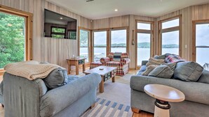 A cozy living room with a large window, a ceiling fan, and a fireplace. - Sunny 'providence Cottage' Retreat w/ Dock, Kayaks (Sunrise Beach)