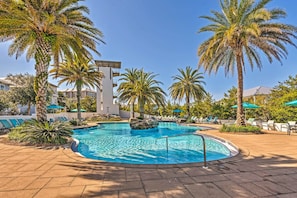 A swimming pool surrounded by palm trees and lounge chairs.